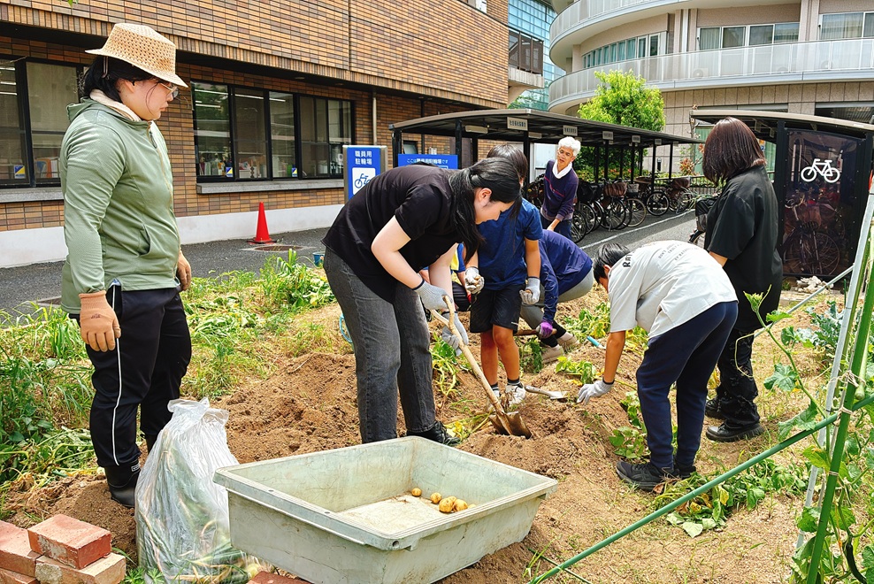 家庭菜園で苗の植え付けをする子供たちの写真
